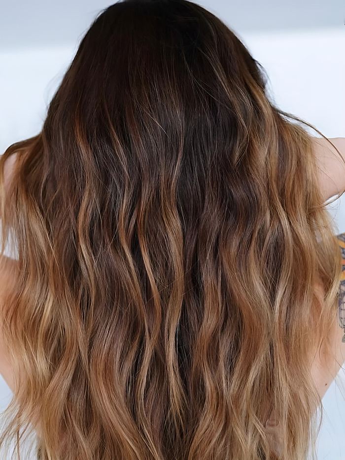 Balayage caramel sur cheveux bruns ondulés